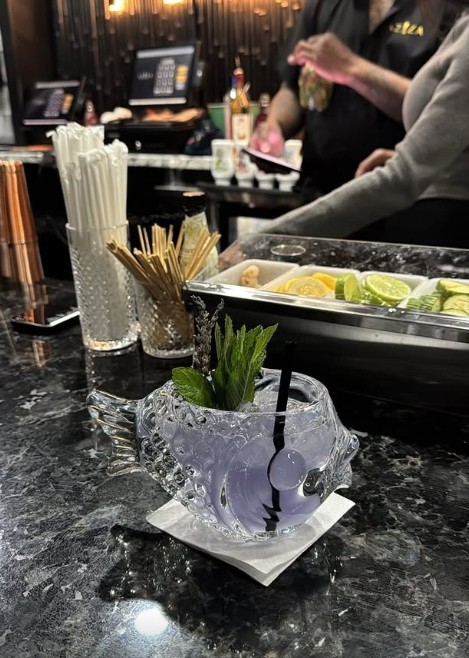 Signature cocktail served in a fish-shaped glass with fresh mint at the Aziza bar
