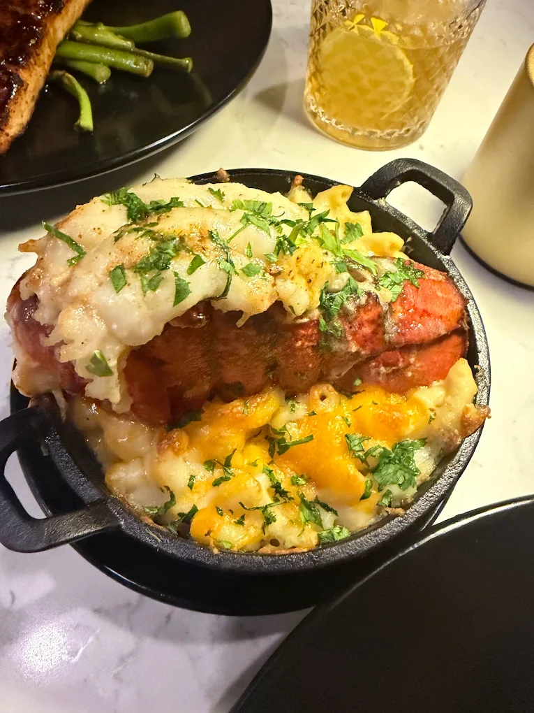 Lobster tail over baked mac and cheese in a cast-iron dish